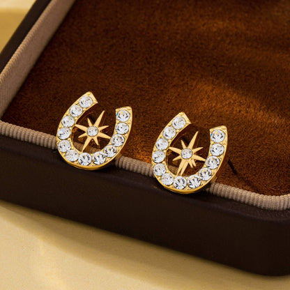 Gold horseshoe earrings with star designs on a brown velvet surface