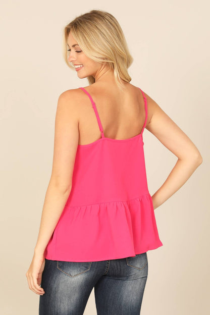 Woman wearing a bright pink tank top and blue jeans on a beige background