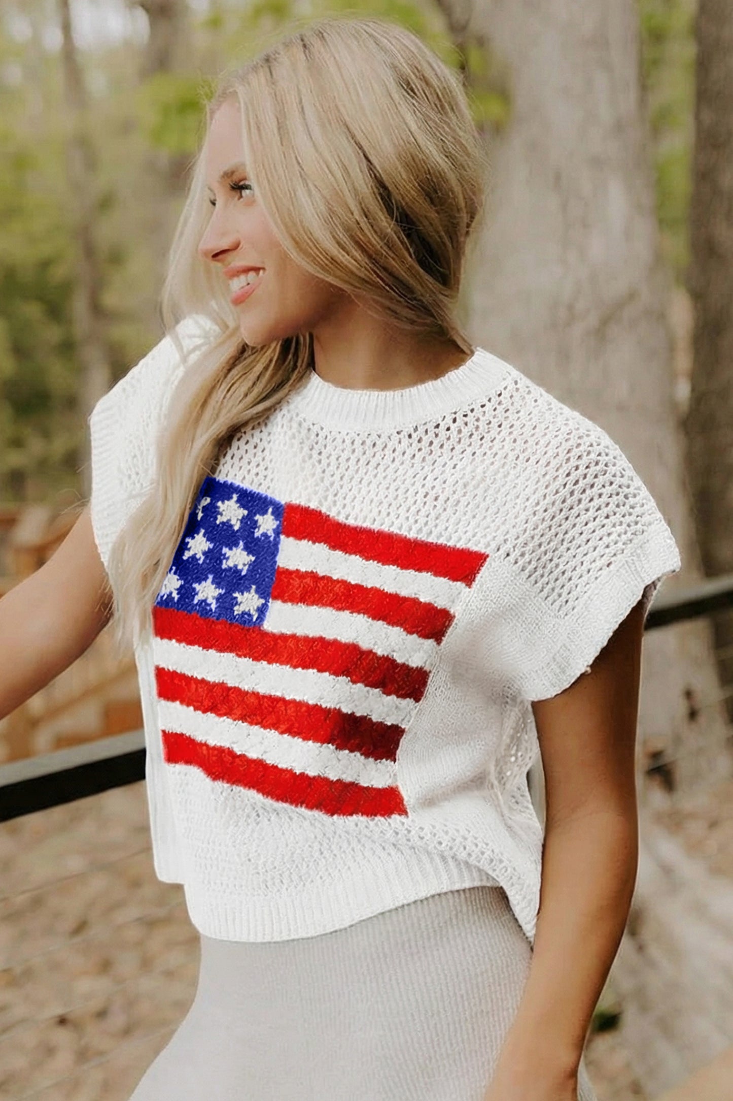 Woman wearing a white crochet top with an American flag design outdoors.