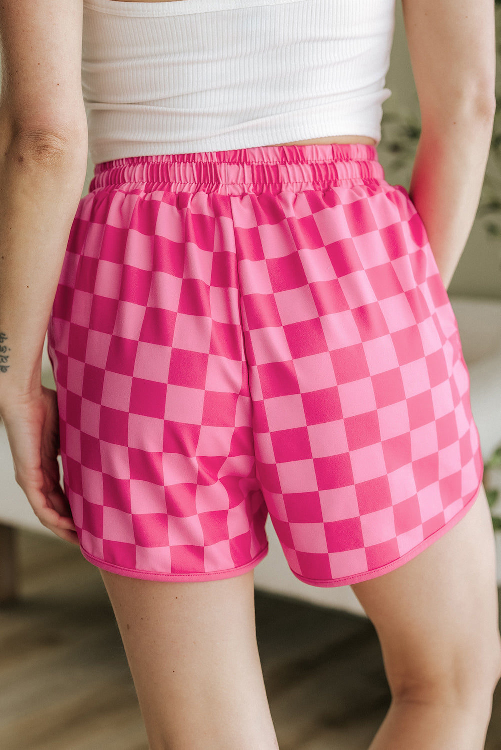 Person wearing pink checkered shorts with a blurred background
