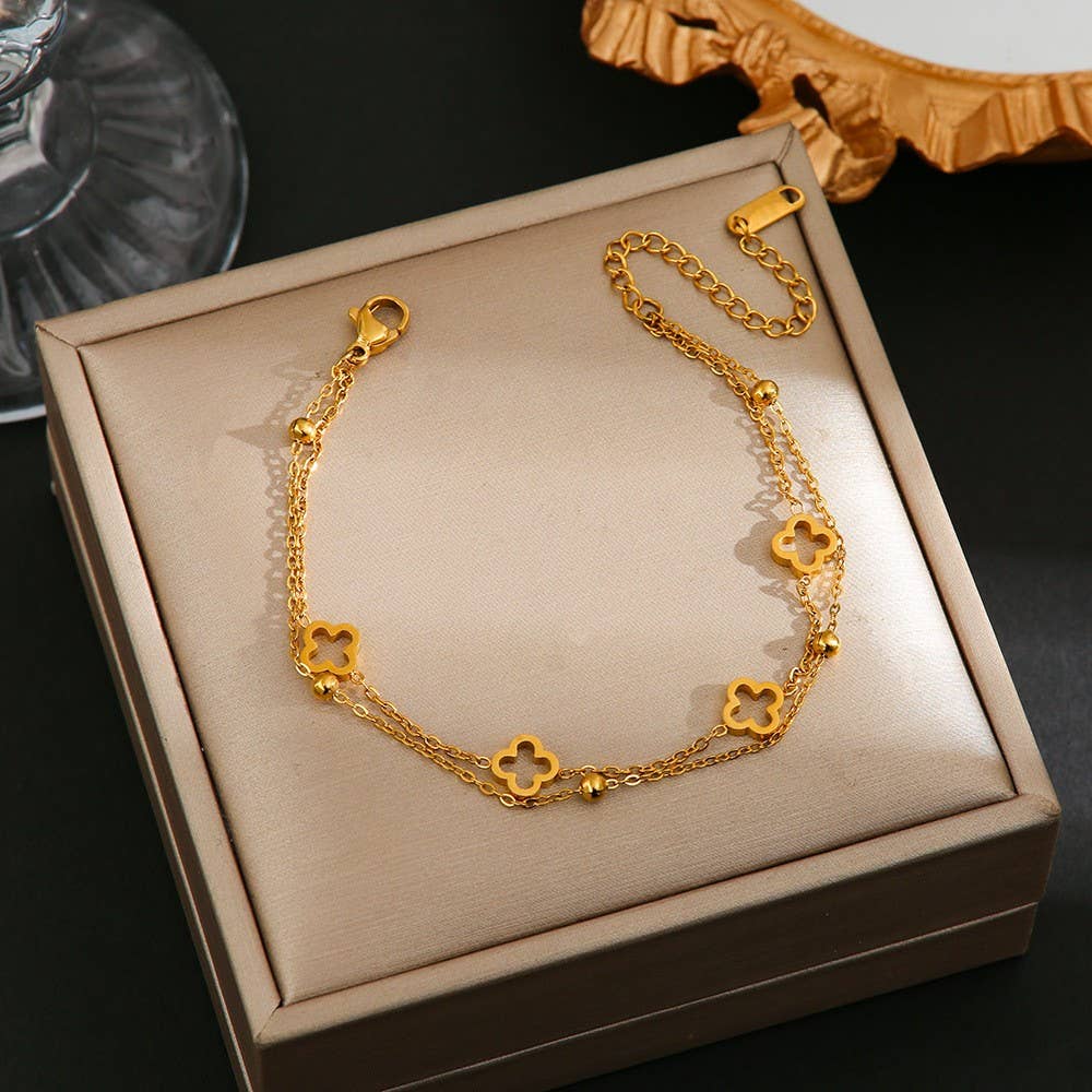 Gold bracelet with clover designs on a beige jewelry box