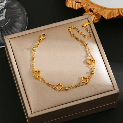 Gold bracelet with clover designs on a beige jewelry box