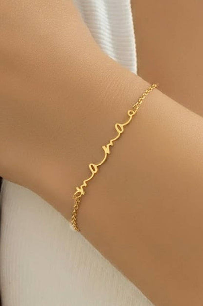 Model wearing the Everly gold Mama script bracelet on her wrist
