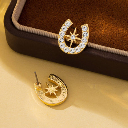 Gold horseshoe and star earrings on a brown cushioned jewelry box.