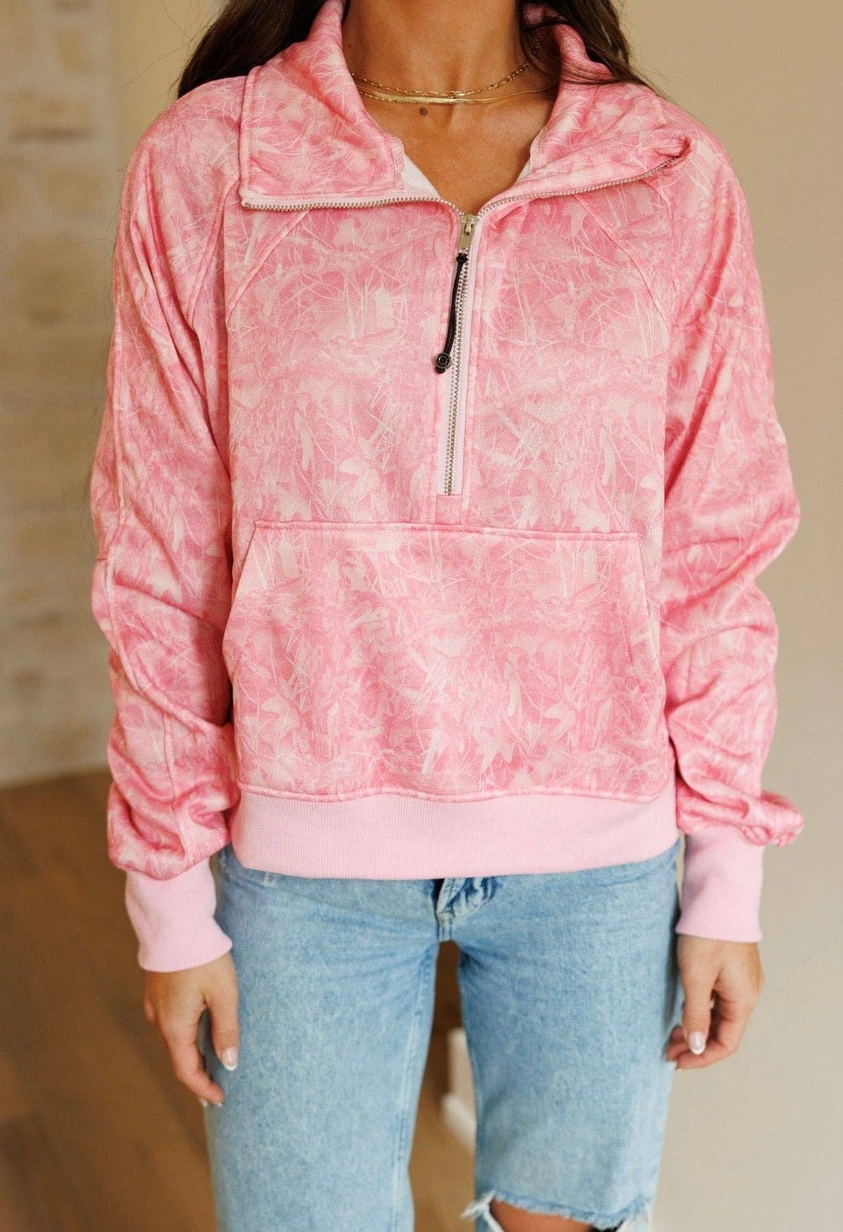 Close-up of pink camouflage pullover with quarter-zip neckline