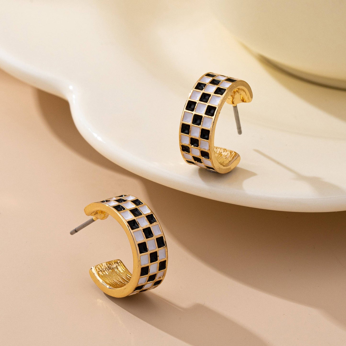 Sloane black-and-white checkered enamel hoop earrings shown from an angled view
