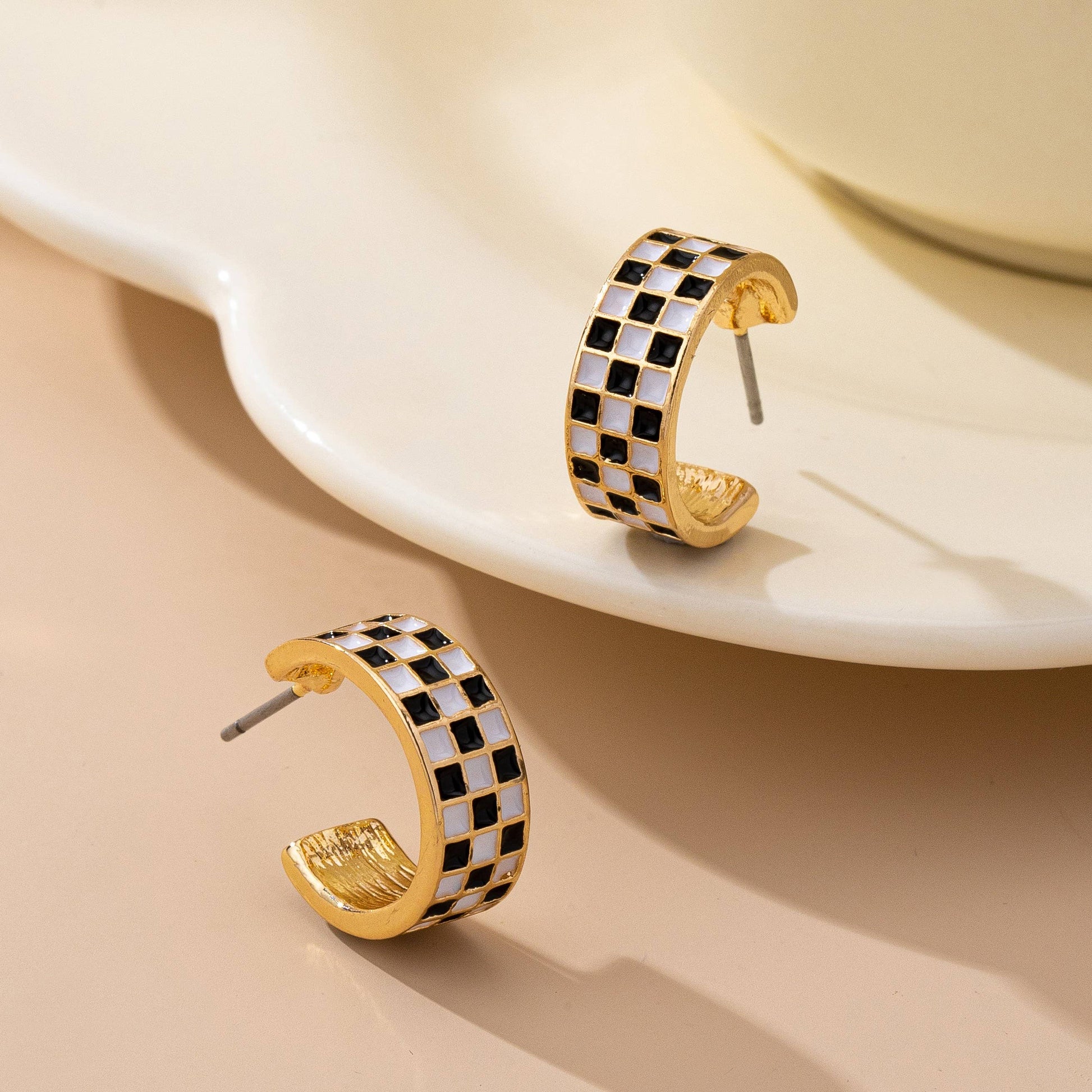 Sloane black-and-white checkered enamel hoop earrings shown from an angled view

