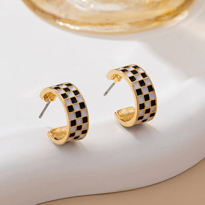 Front view of Sloane checkerboard huggie hoop earrings with gold-tone edges
