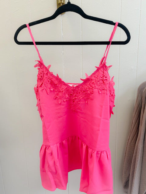 Pink lace top on a hanger against a white wall
