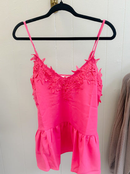 Pink lace top on a hanger against a white wall
