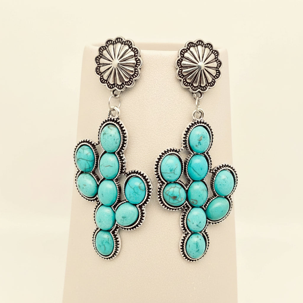 Turquoise and silver earrings on a beige display card