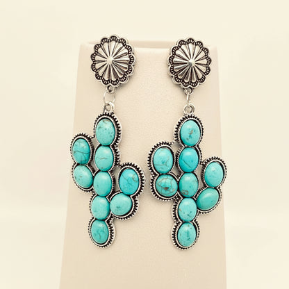Turquoise and silver earrings on a beige display card
